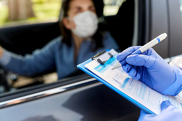 Image showing healthcare worker with clipboard and woman in car