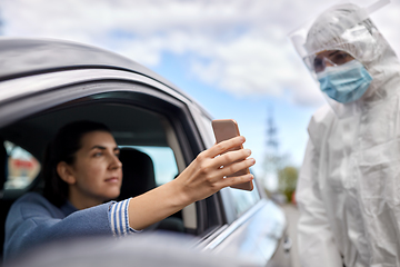 Image showing woman in car showing phone to healthcare worker