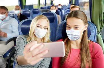 Image showing women in medical masks taking selfie in travel bus