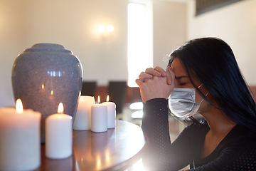 Image showing sad woman in mask praying at funeral in church