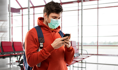 Image showing man in mask with cellphone and backpack at airport