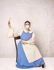 Image showing Medieval young woman as a lady milkmade wearing protective mask against coronavirus spread