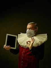 Image showing Senior man as a medieval knight on dark background wearing protective mask against coronavirus