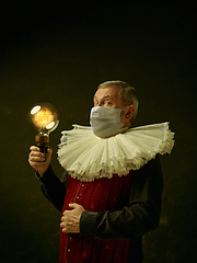 Image showing Senior man as a medieval knight on dark background wearing protective mask against coronavirus