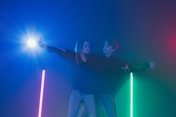 Image showing Cheering dance party, performance concept. Couple dancing with neon lights raised hands up