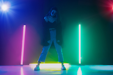 Image showing Young caucasian girl posing stylish in neon light on dark background