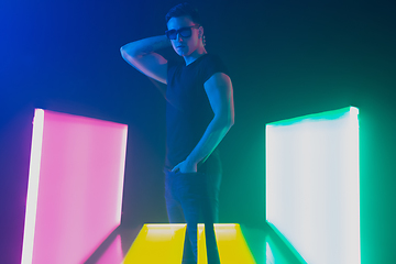 Image showing Young caucasian man posing stylish in neon light on dark background