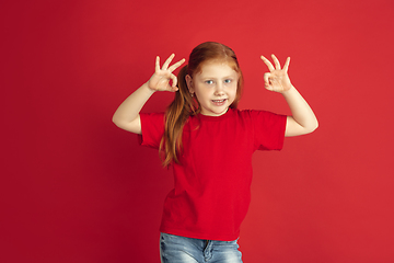 Image showing Caucasian little girl portrait isolated on red studio background, emotions concept