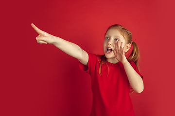 Image showing Caucasian little girl portrait isolated on red studio background, emotions concept