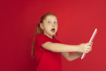 Image showing Caucasian little girl portrait isolated on red studio background, emotions concept