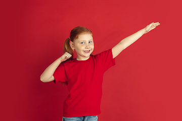 Image showing Caucasian little girl portrait isolated on red studio background, emotions concept