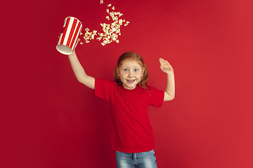 Image showing Caucasian little girl portrait isolated on red studio background, emotions concept