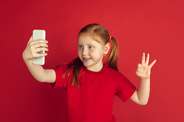 Image showing Caucasian little girl portrait isolated on red studio background, emotions concept