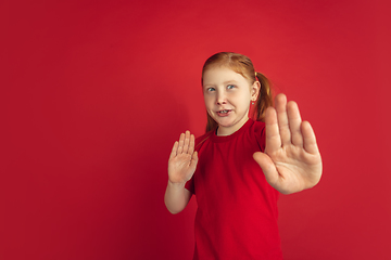 Image showing Caucasian little girl portrait isolated on red studio background, emotions concept