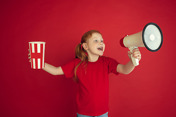 Image showing Caucasian little girl portrait isolated on red studio background, emotions concept