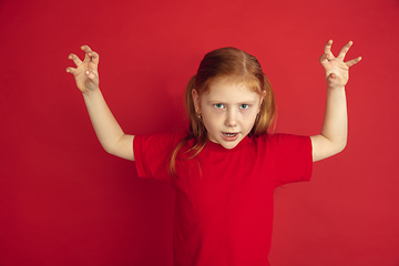 Image showing Caucasian little girl portrait isolated on red studio background, emotions concept