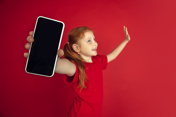 Image showing Caucasian little girl portrait isolated on red studio background, emotions concept