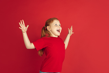 Image showing Caucasian little girl portrait isolated on red studio background, emotions concept