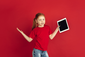 Image showing Caucasian little girl portrait isolated on red studio background, emotions concept