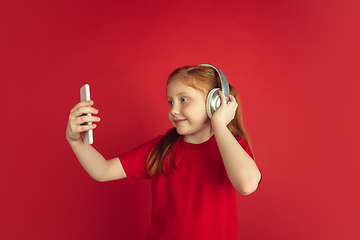 Image showing Caucasian little girl portrait isolated on red studio background, emotions concept