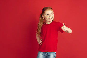 Image showing Caucasian little girl portrait isolated on red studio background, emotions concept