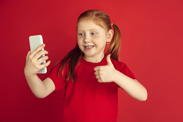 Image showing Caucasian little girl portrait isolated on red studio background, emotions concept