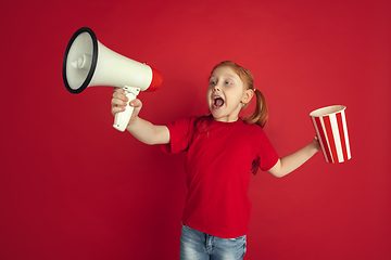 Image showing Caucasian little girl portrait isolated on red studio background, emotions concept