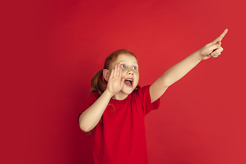 Image showing Caucasian little girl portrait isolated on red studio background, emotions concept