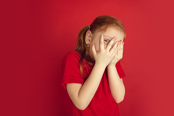 Image showing Caucasian little girl portrait isolated on red studio background, emotions concept