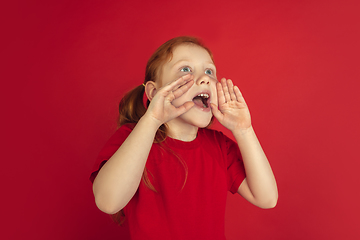 Image showing Caucasian little girl portrait isolated on red studio background, emotions concept