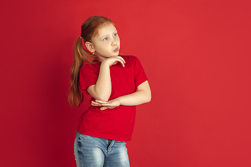 Image showing Caucasian little girl portrait isolated on red studio background, emotions concept