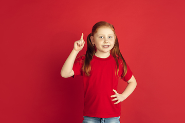 Image showing Caucasian little girl portrait isolated on red studio background, emotions concept