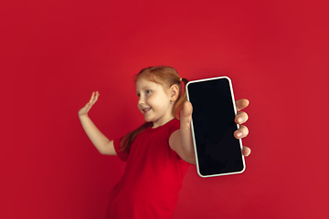 Image showing Caucasian little girl portrait isolated on red studio background, emotions concept