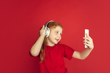 Image showing Caucasian little girl portrait isolated on red studio background, emotions concept