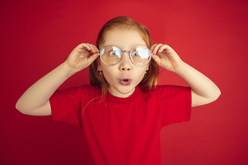 Image showing Caucasian little girl portrait isolated on red studio background, emotions concept