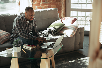 Image showing African-american man, freelancer during the work in home office while quarantine