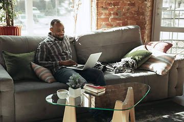 Image showing African-american man, freelancer during the work in home office while quarantine