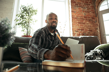 Image showing African-american man, freelancer during the work in home office while quarantine