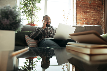 Image showing African-american man, freelancer during the work in home office while quarantine