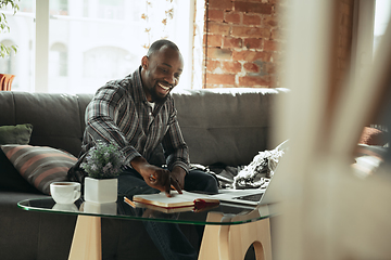 Image showing African-american man, freelancer during the work in home office while quarantine