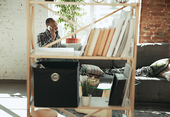 Image showing African-american man, freelancer during the work in home office while quarantine