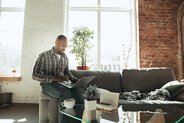 Image showing African-american man, freelancer during the work in home office while quarantine