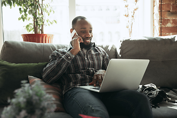 Image showing African-american man, freelancer during the work in home office while quarantine