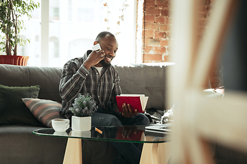 Image showing African-american man, freelancer during the work in home office while quarantine