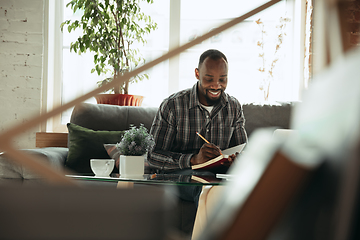 Image showing African-american man, freelancer during the work in home office while quarantine