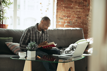 Image showing African-american man, freelancer during the work in home office while quarantine