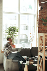 Image showing African-american man, freelancer during the work in home office while quarantine