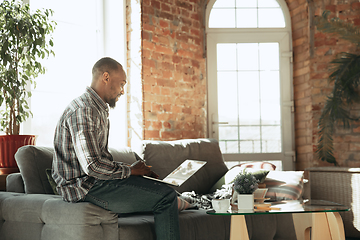 Image showing African-american man, freelancer during the work in home office while quarantine