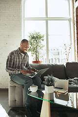 Image showing African-american man, freelancer during the work in home office while quarantine