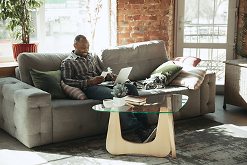 Image showing African-american man, freelancer during the work in home office while quarantine